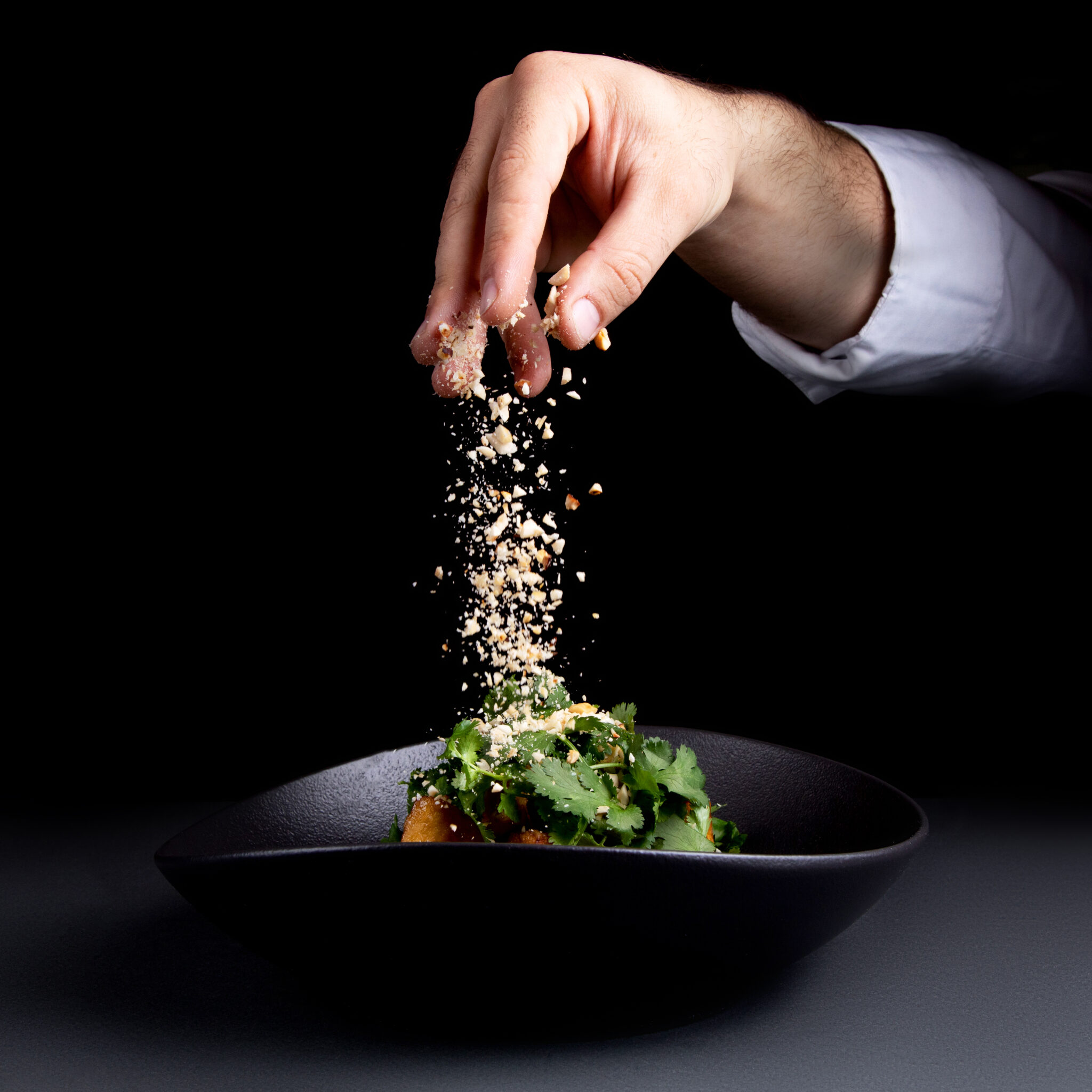 the chef sprinkles the salad with nuts